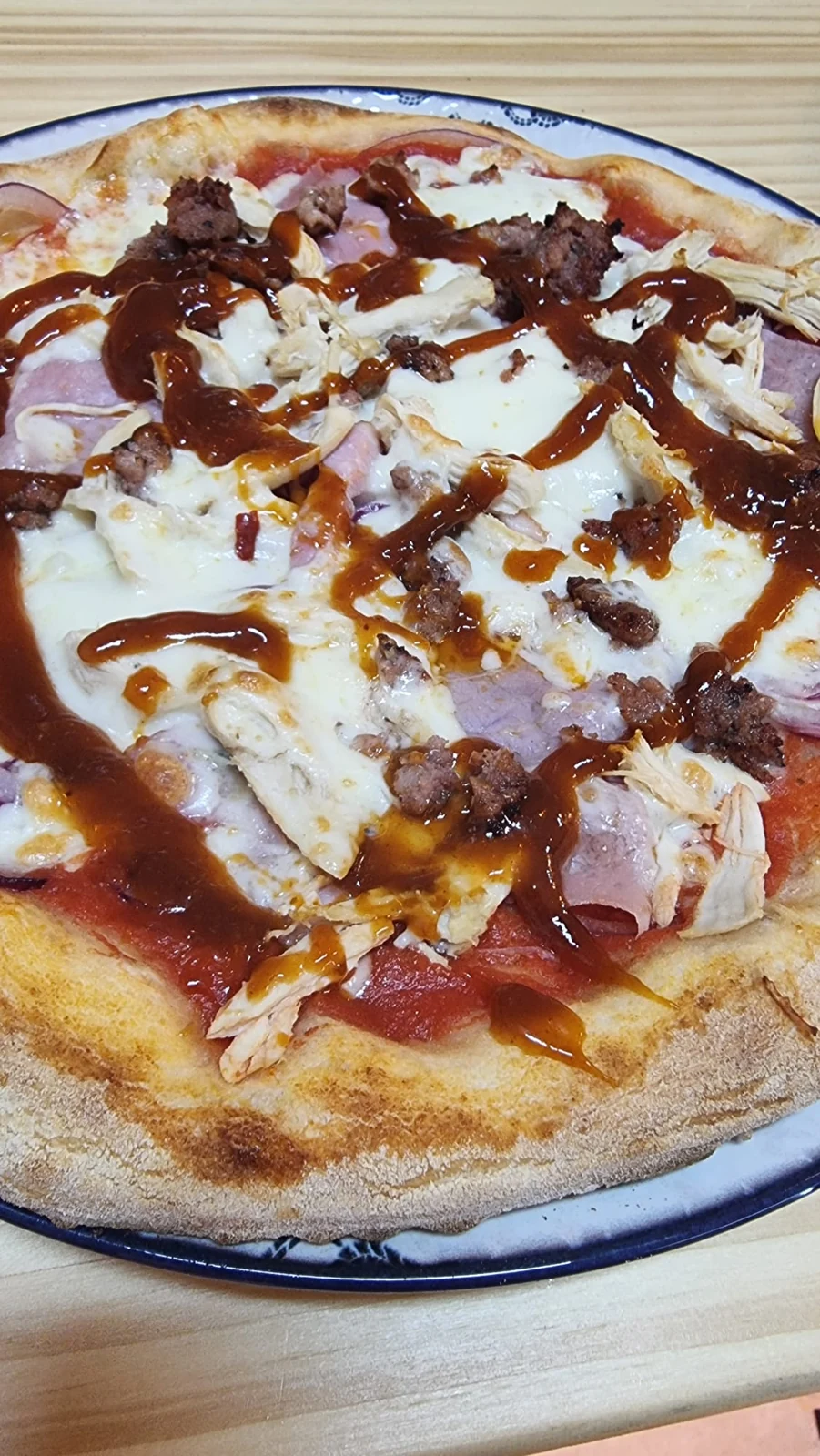 Detalle de la pizza con queso fundido, carne y salsa barbacoa